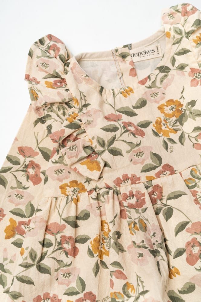 Vestido floral para niña pequeña con hombros con volantes en tonos crema, rosa y naranja.