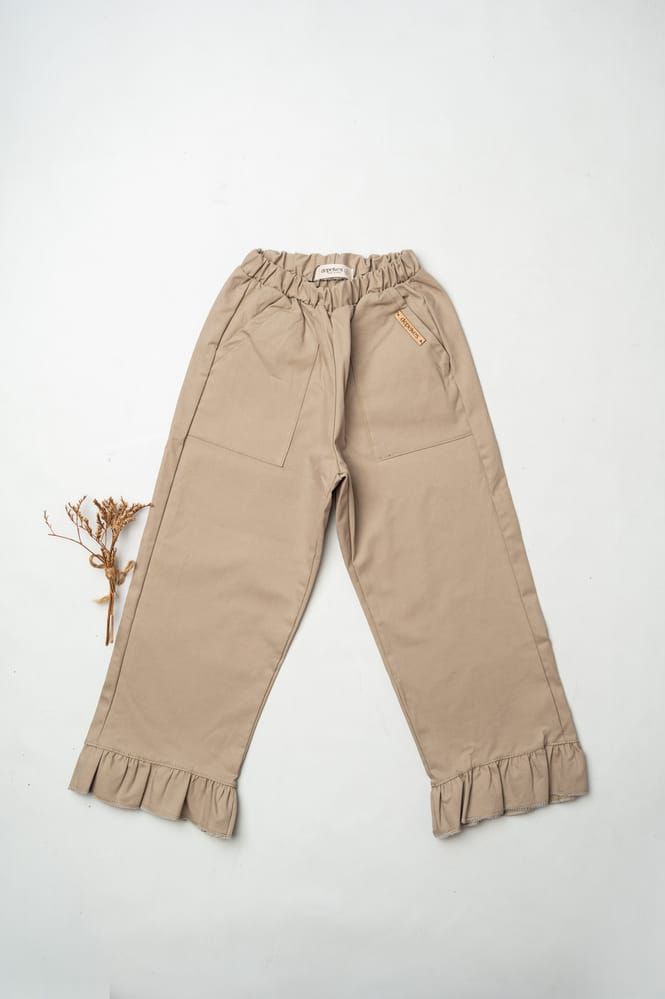 Pantalones beige con volantes, cintura y puños elásticos, extendidos sobre un fondo blanco.
