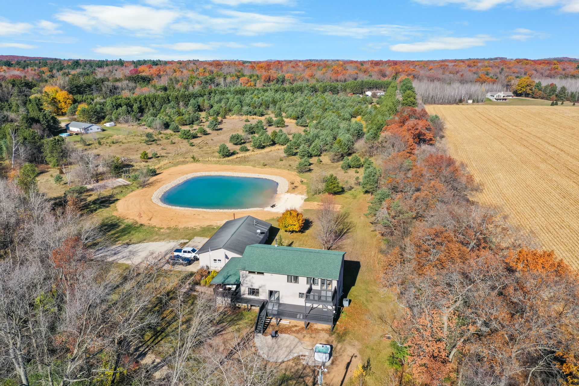 A green putting green in the middle of a lush green field in front of a house.