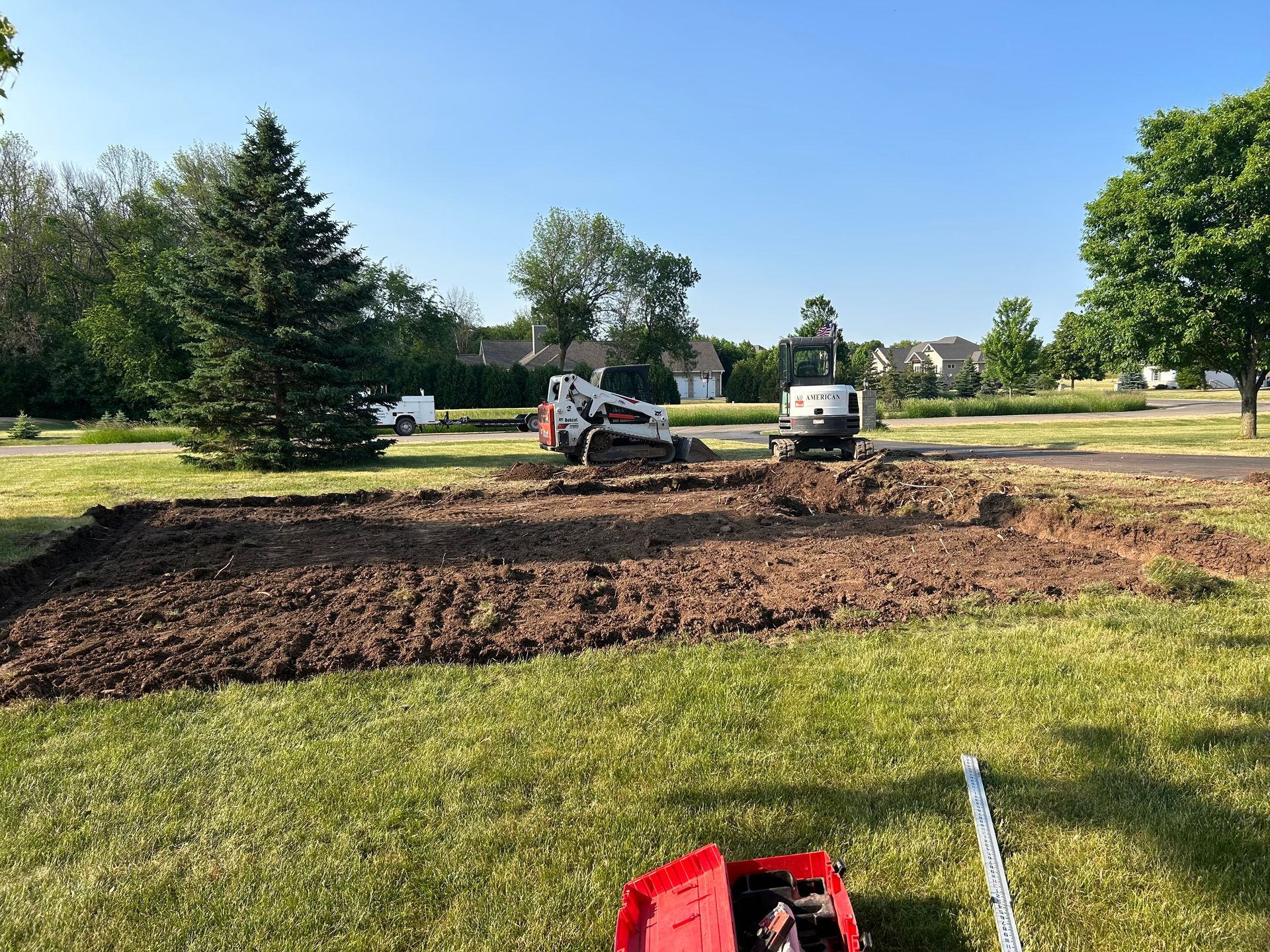 skid loader and mini-excavator clearing a pad for a new construction project