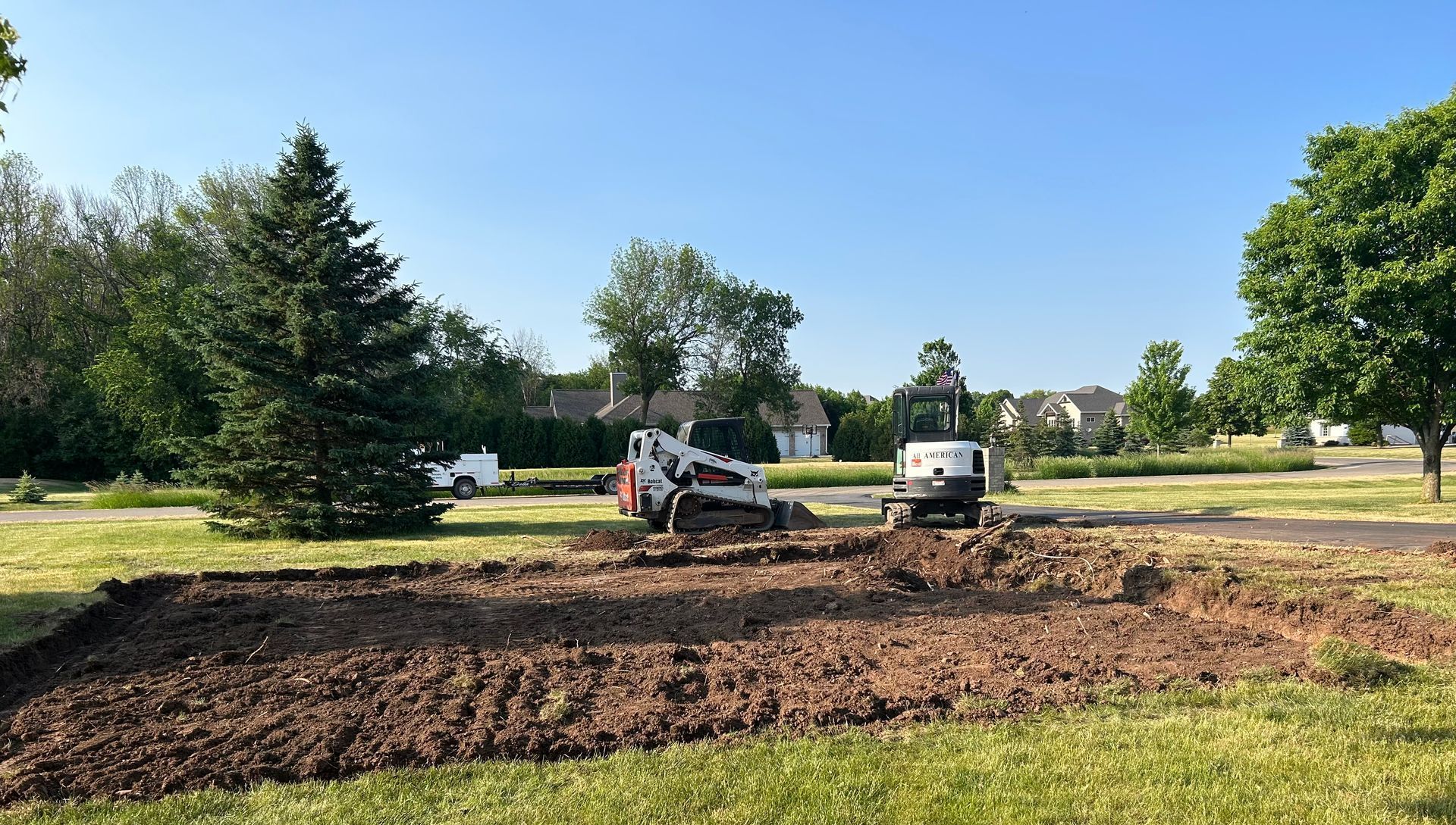 A bulldozer is digging a hole in a grassy field.