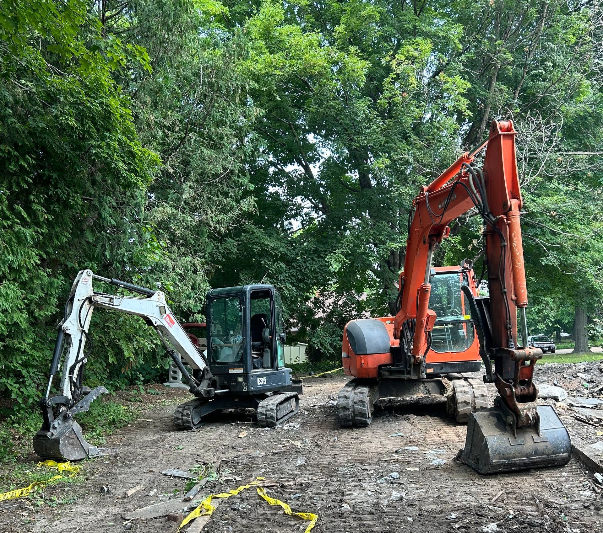 Two excavators are parked next to each other in a dirt field.