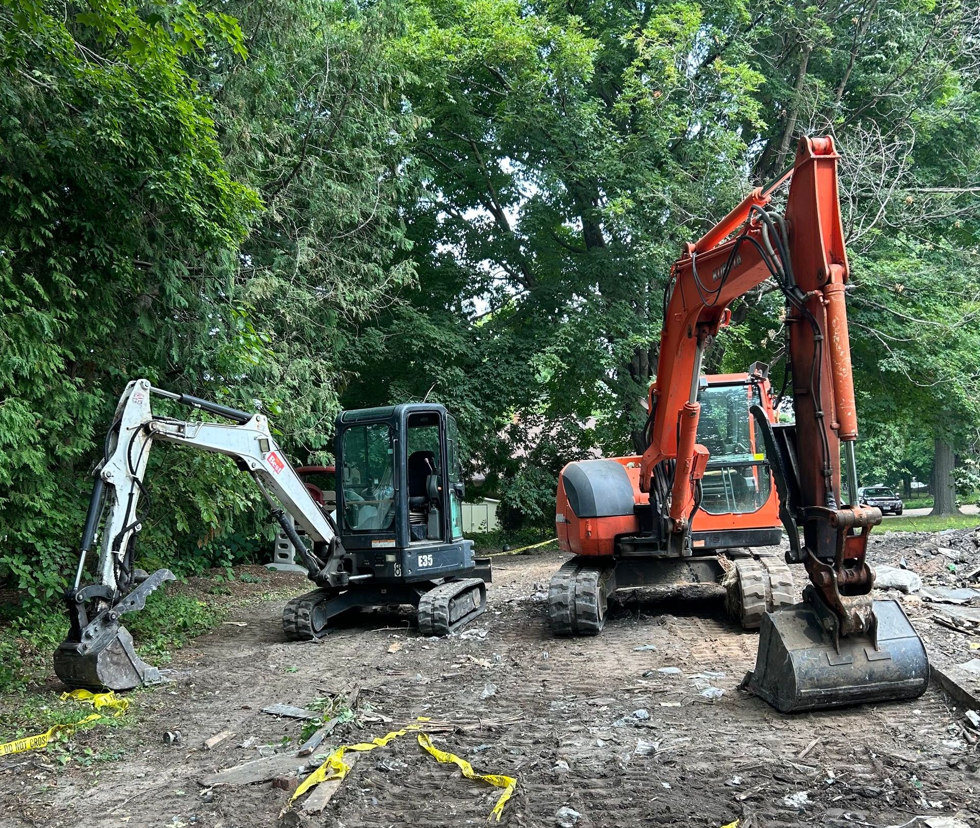 Two excavators are parked next to each other in a dirt lot.