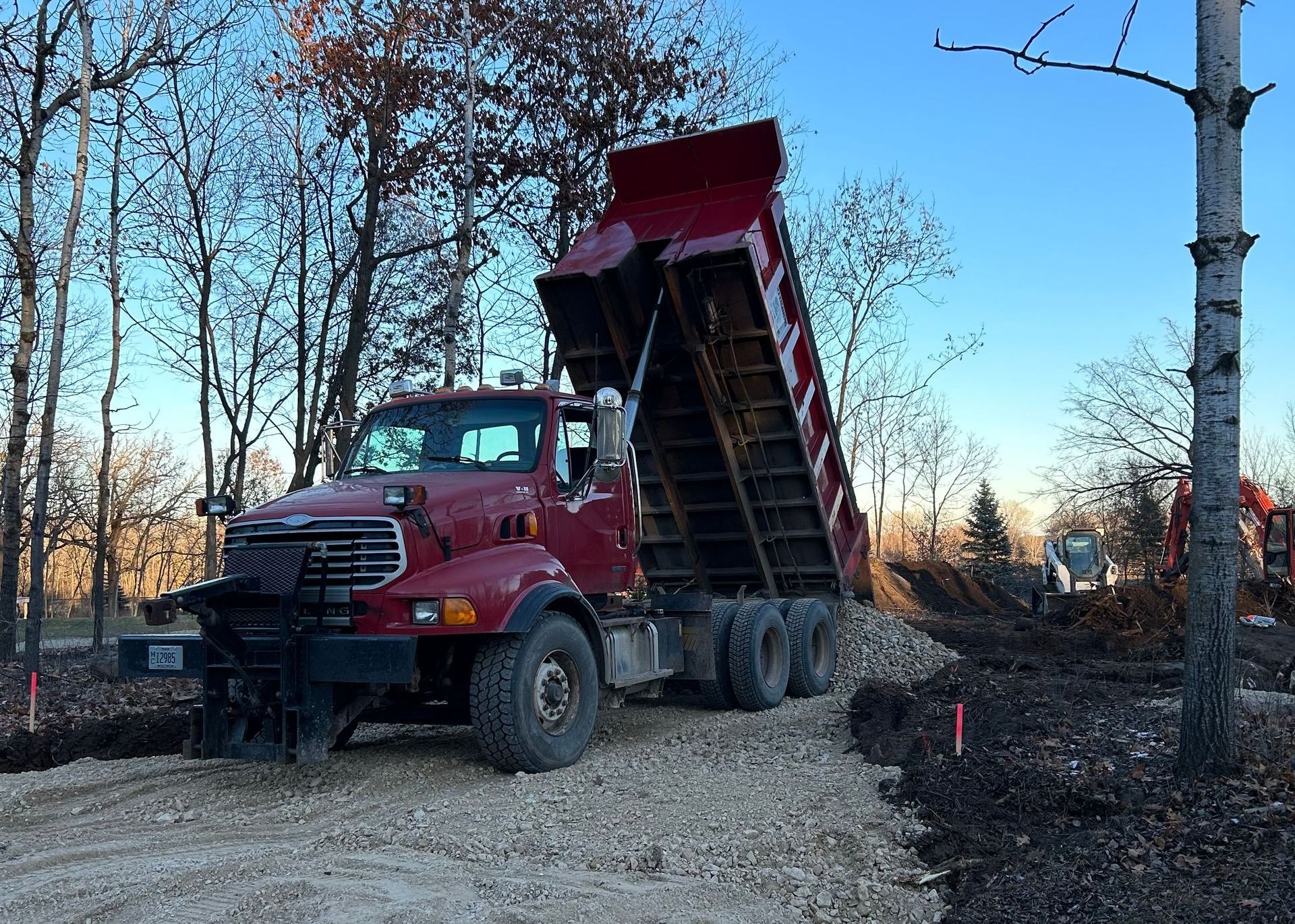A red dump truck is driving down a dirt road.