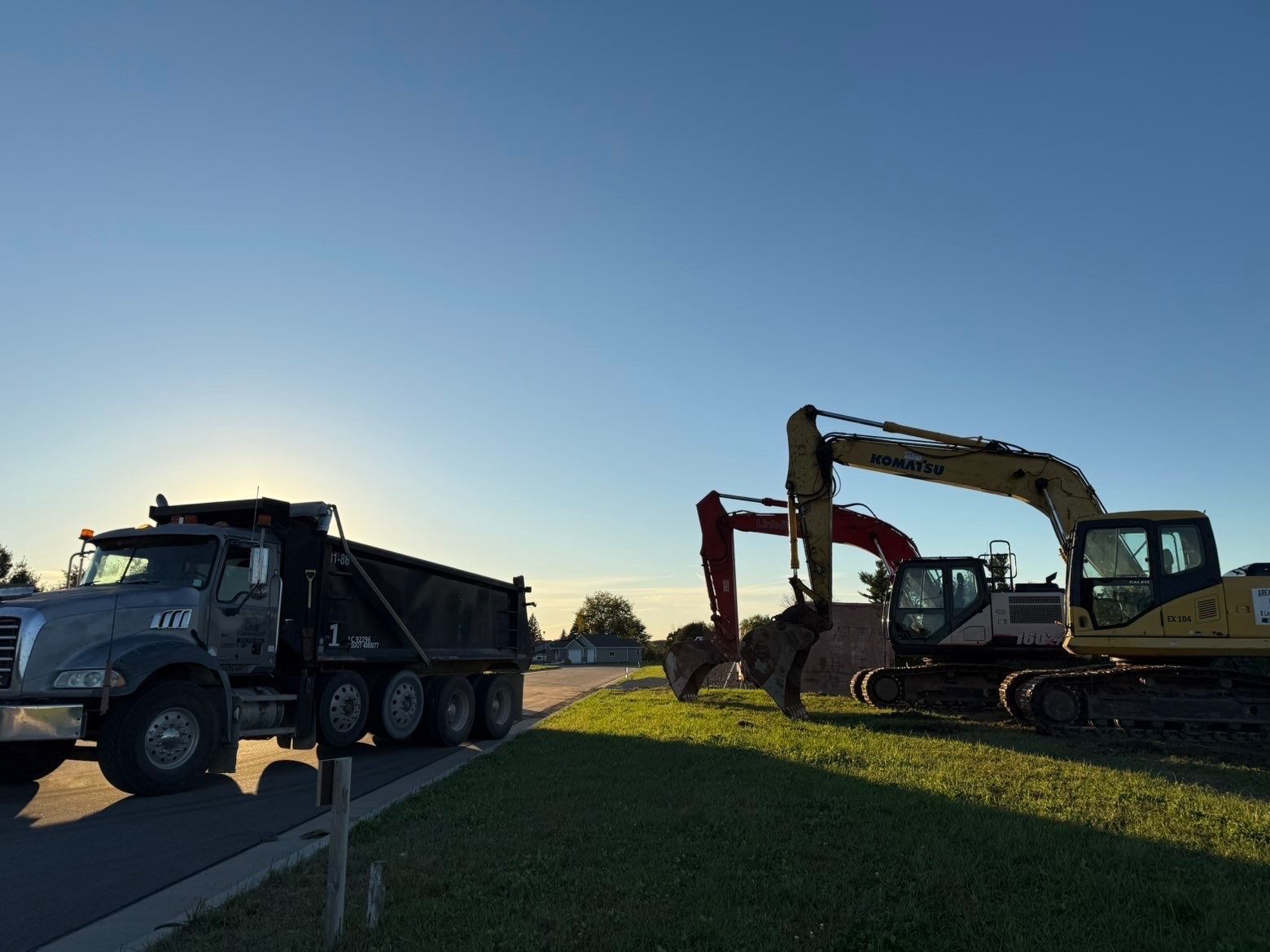 A bulldozer and an excavator are working in a dirt field.