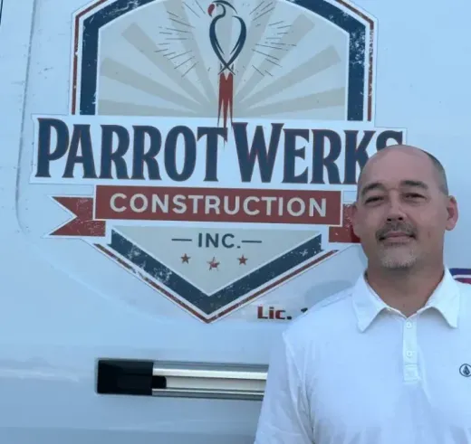 Man stands in front of a vehicle with the Parrot Werks Construction logo. He wears a white polo shirt, smiles.