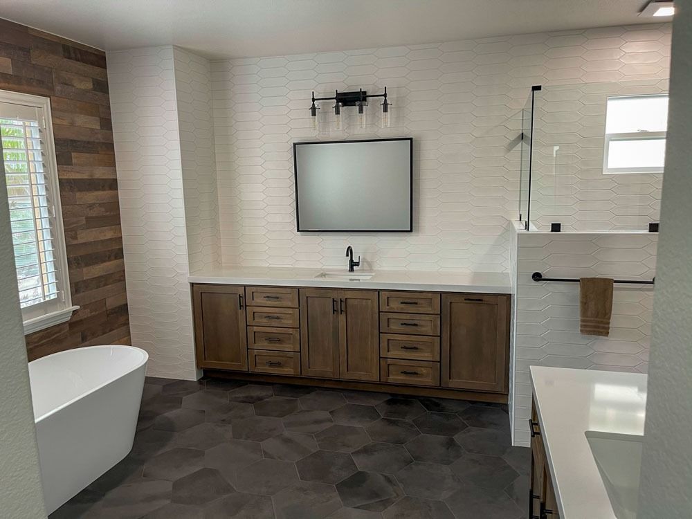 Modern bathroom with wooden vanity, white tub, and textured dark grey flooring. White and wood-toned accents.