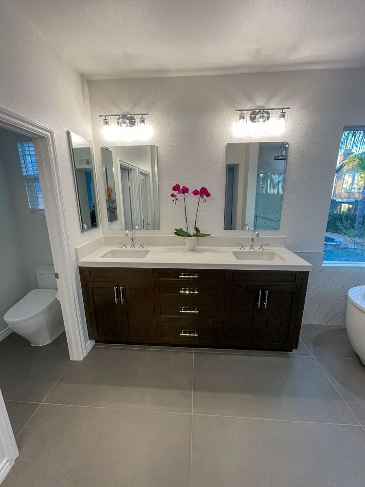 A modern bathroom features a double sink vanity with two mirrors and lighting. A toilet is to the left.