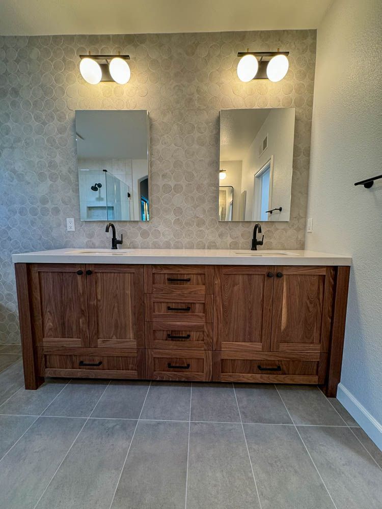 A modern bathroom with a double vanity. The wooden vanity has a light-colored countertop, two mirrors, and black fixtures.