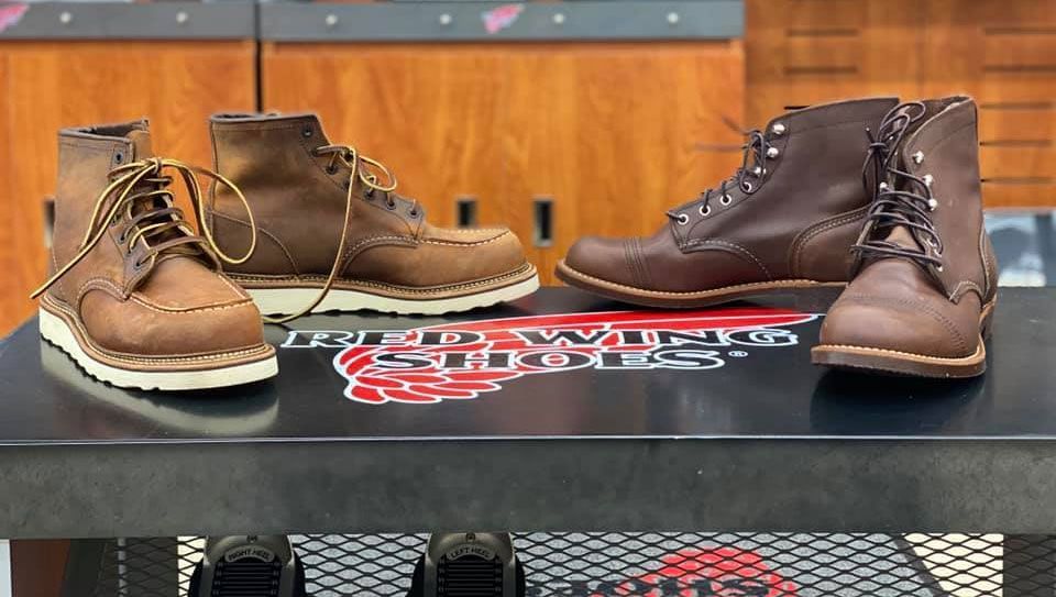 Four pairs of Red Wing boots on a display table. Two pairs are brown leather with white soles, and two are brown leather.