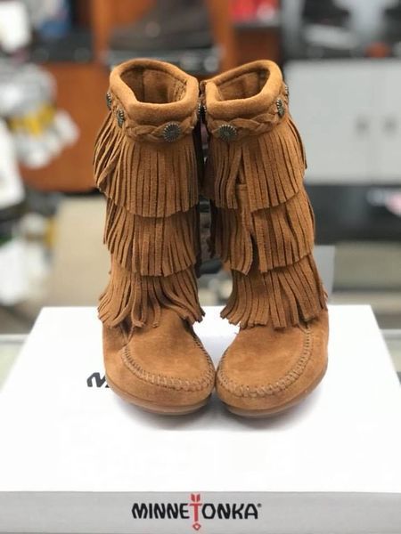 Tan Minnetonka fringed boots on a white box.