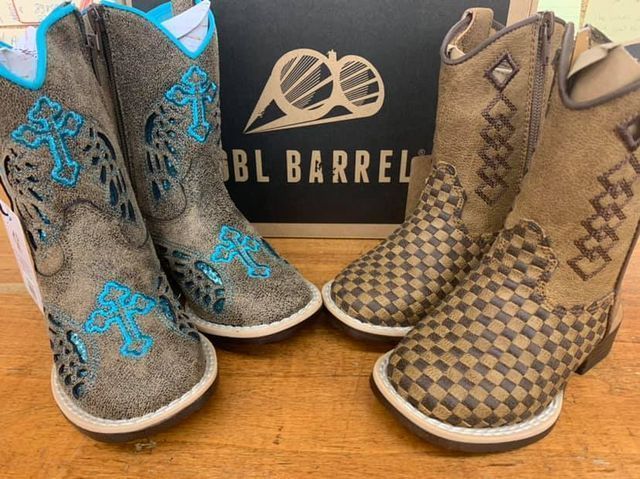 Two pairs of children's cowboy boots. One pair is gray with blue cross design, the other is tan with diamond pattern.