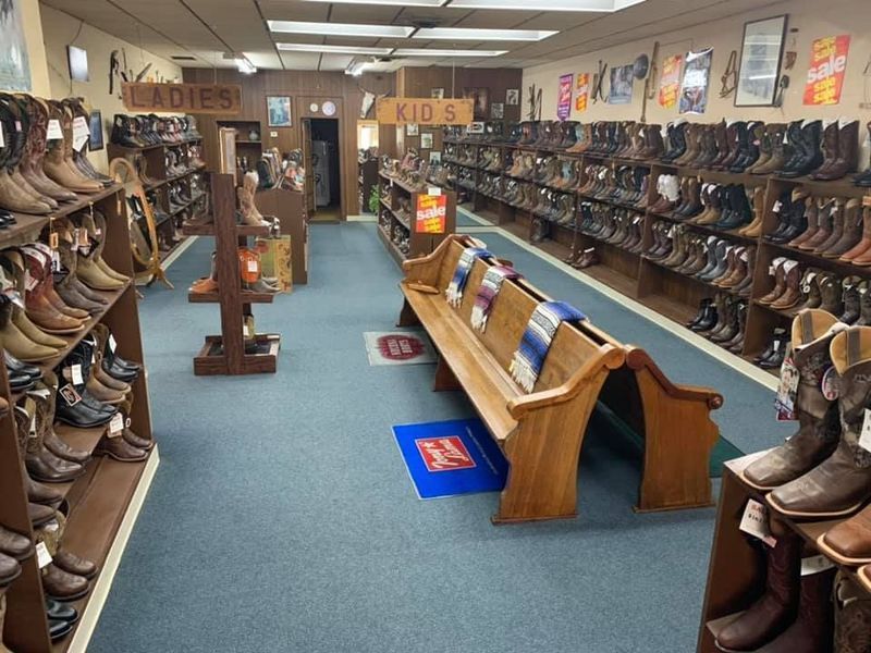 Inside a Western boot store; boots on shelves, benches, blue carpet.