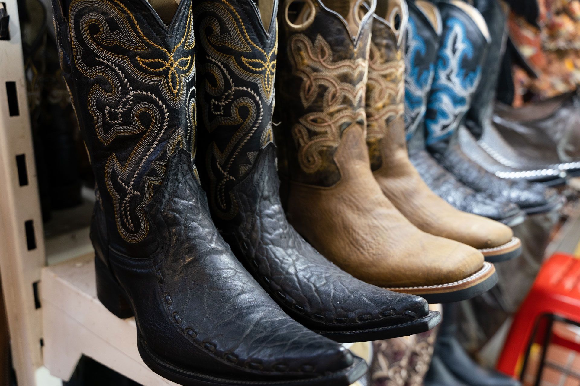 Row of cowboy boots in various colors and designs, on display.