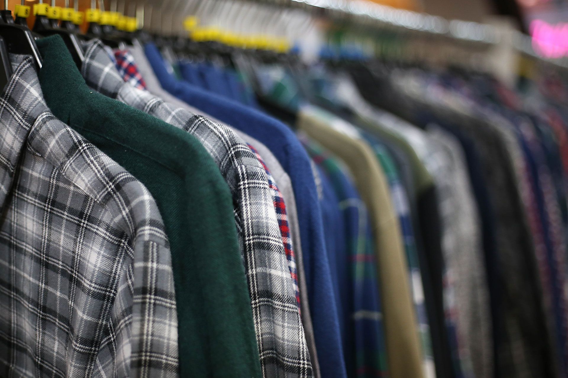 Shirts on hangers, varying colors and patterns, displayed in a store setting.