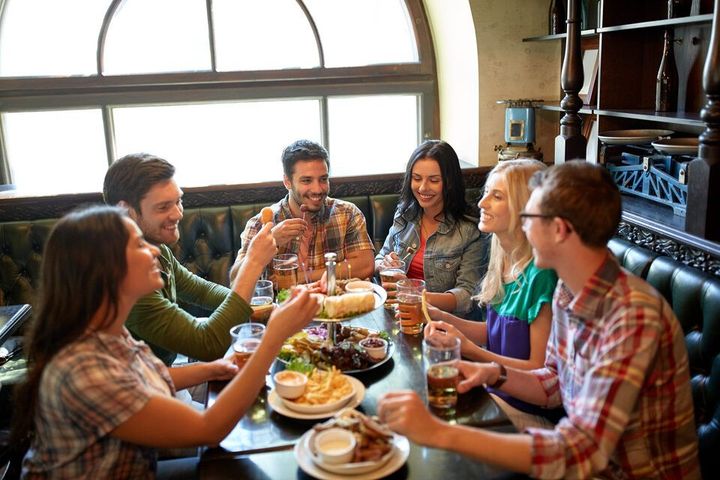 smiling friends having dinner and drinking beer at a restaurant or pub