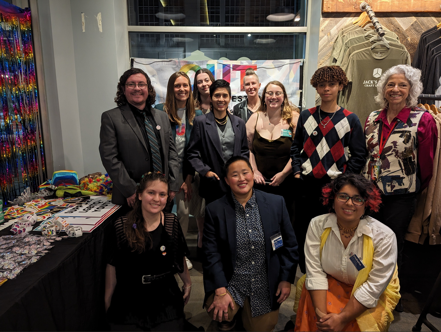 Group of people at a table in front of a banner; they are smiling and looking at the camera.