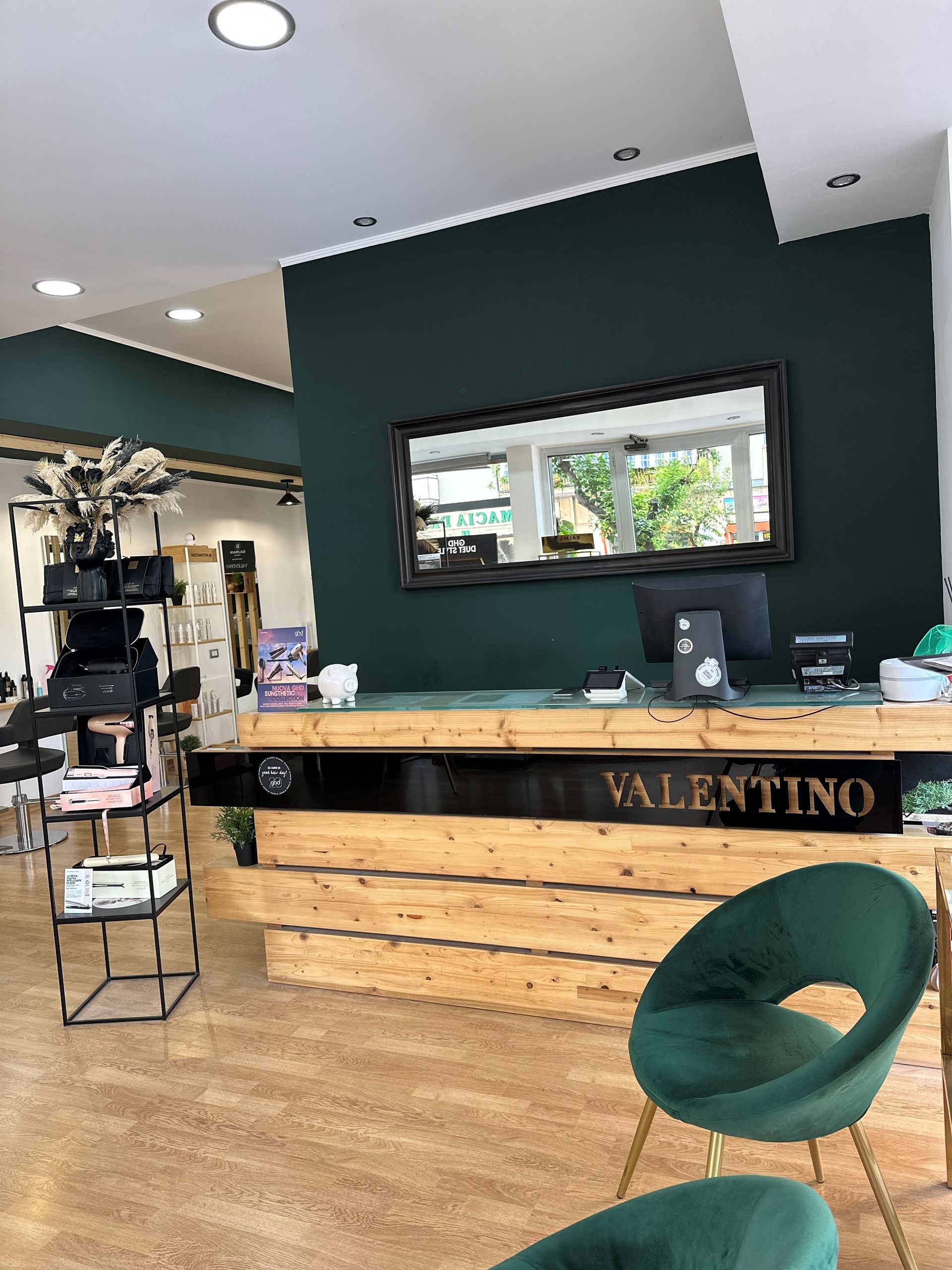 Area reception con parete decorata in legno e verde dietro una scrivania con il nome