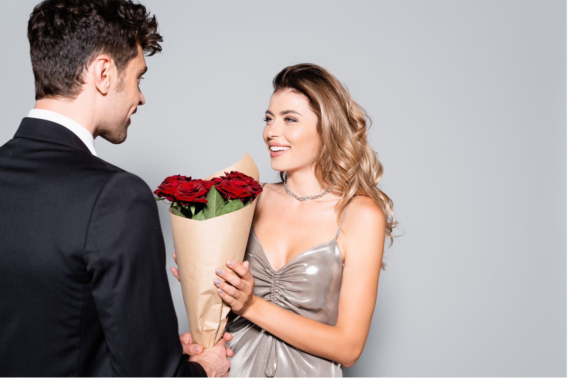Woman in silver dress receiving flowers from man in a suit - love bombing