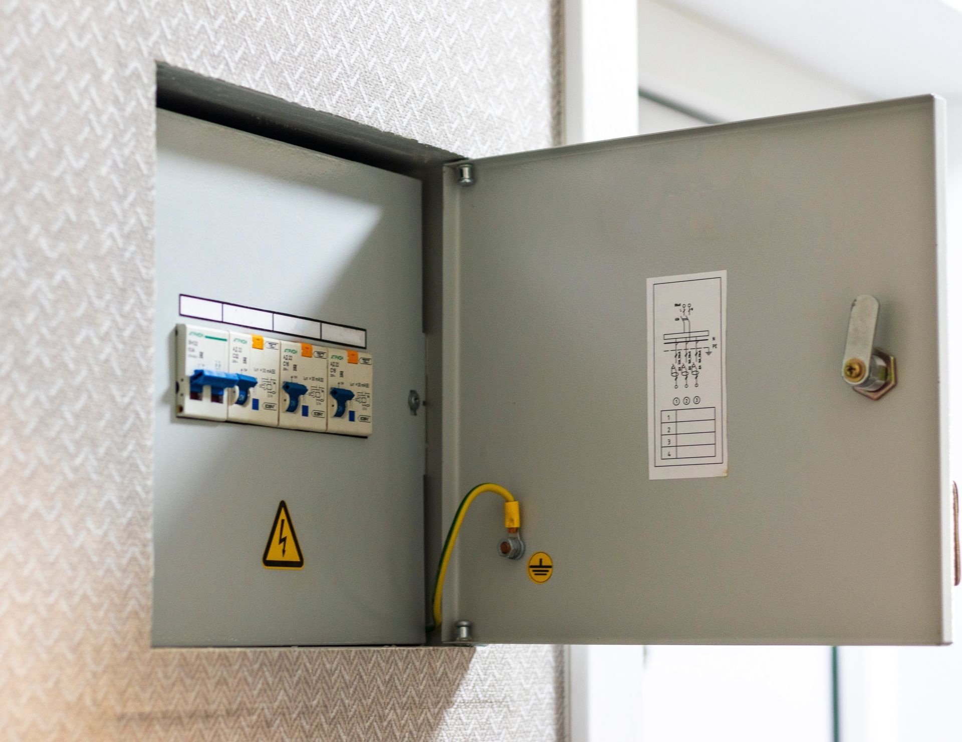 Open electrical breaker box with three circuit breakers mounted on a wall.