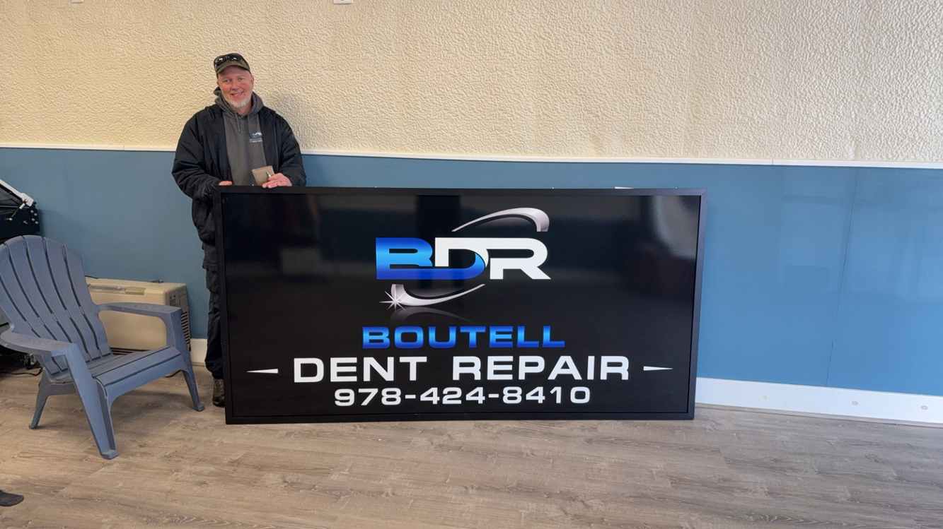 Man stands next to a large sign for