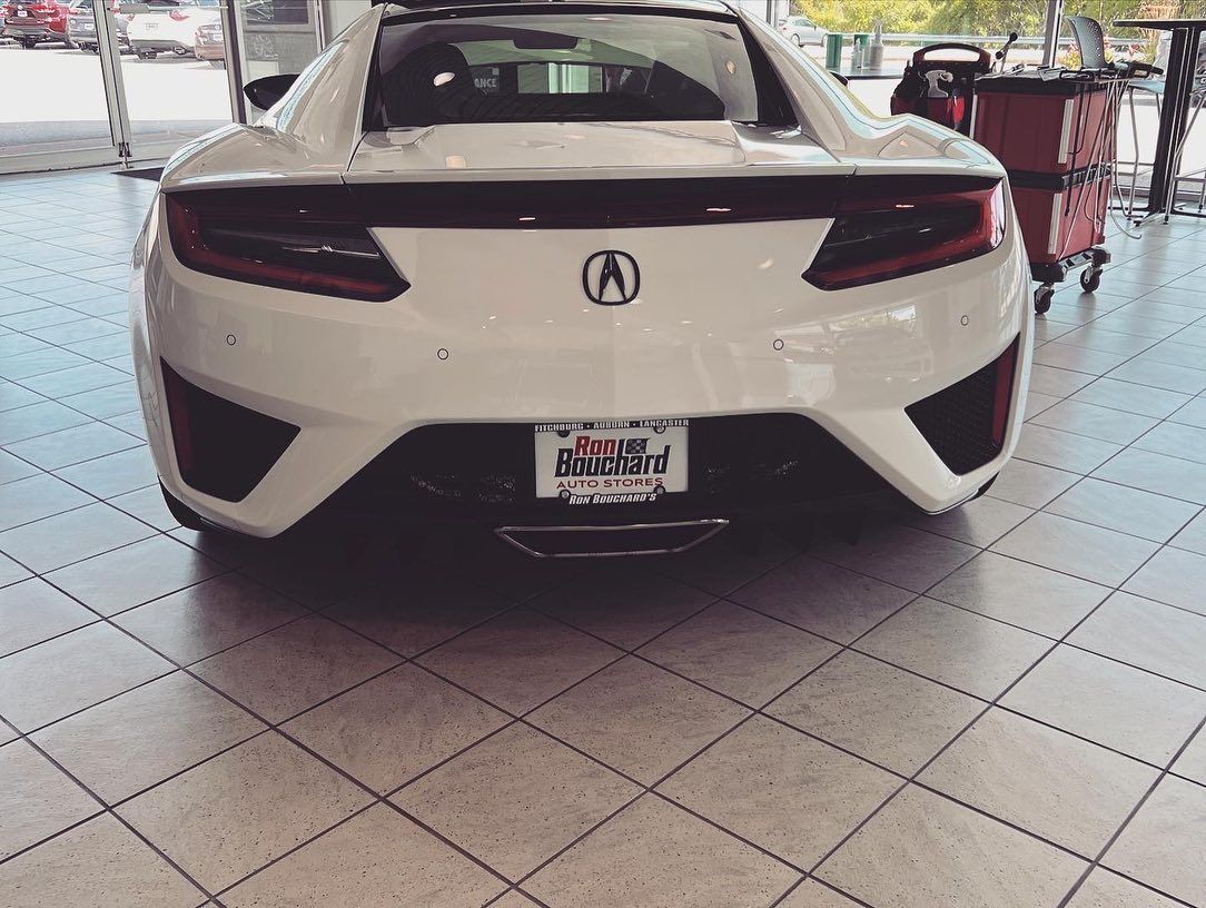 White Acura NSX sports car in a showroom, rear view.