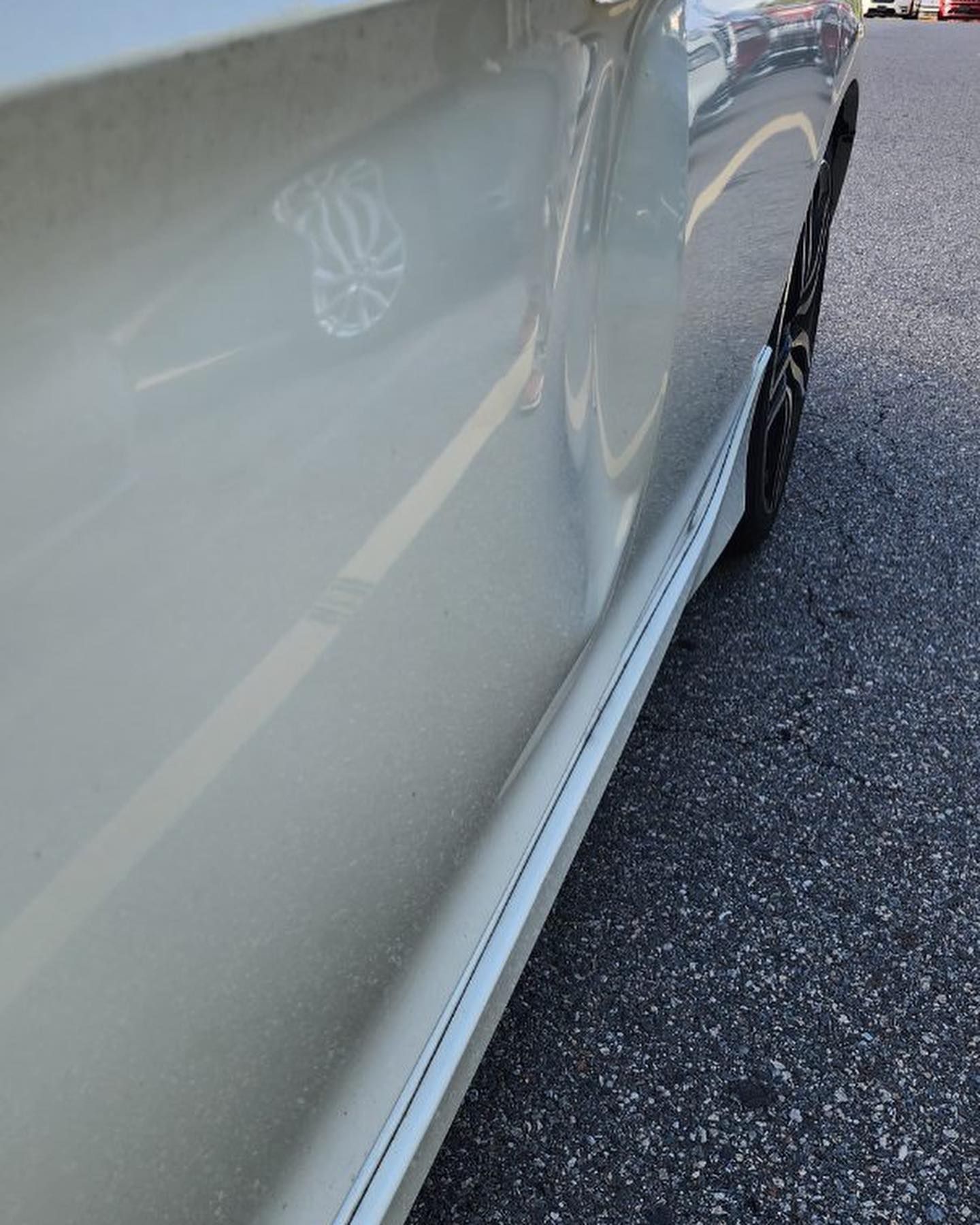 Beige car side with a dent, parked on asphalt.