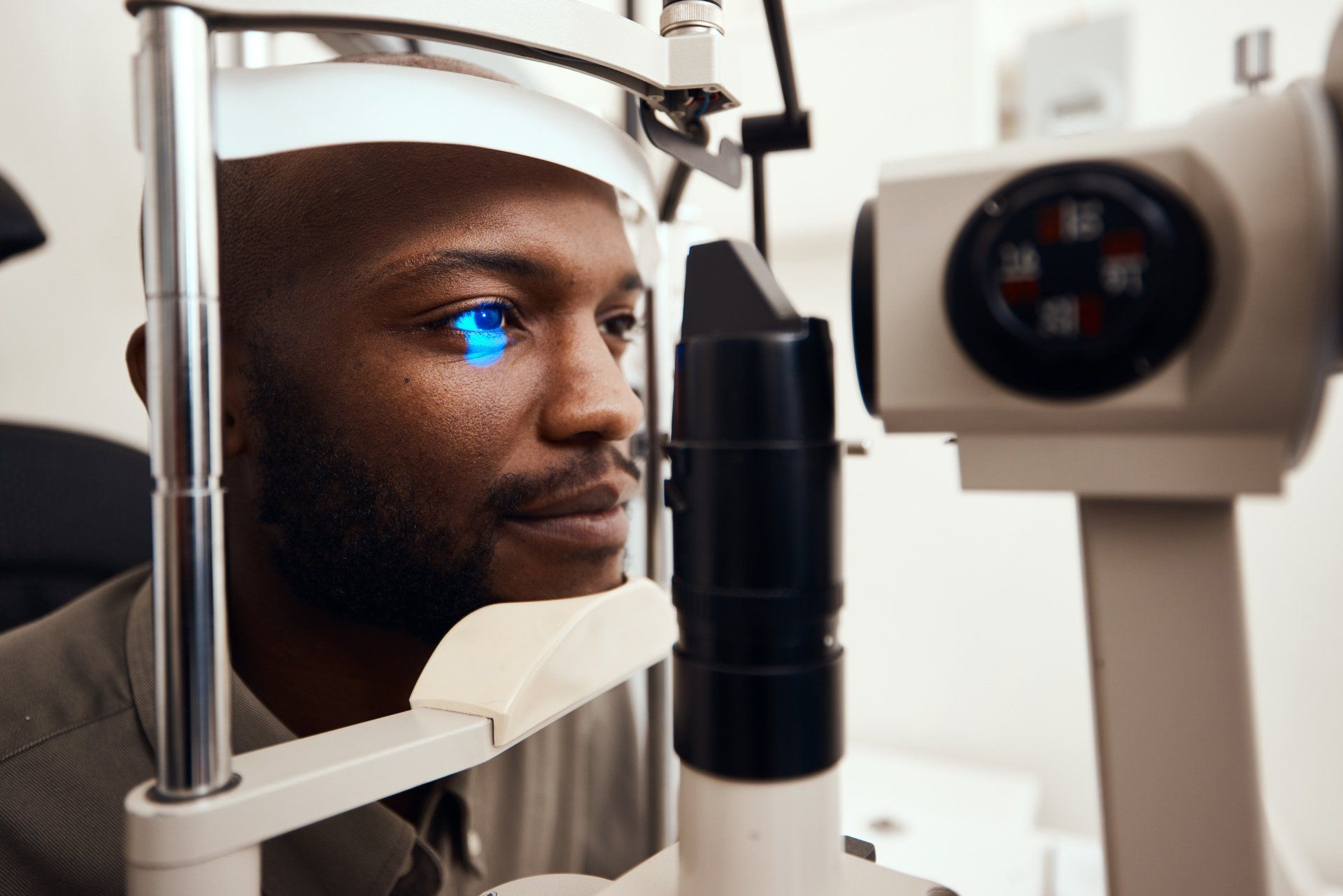 Man having eye exam with a slit lamp, a blue light shining on eye.