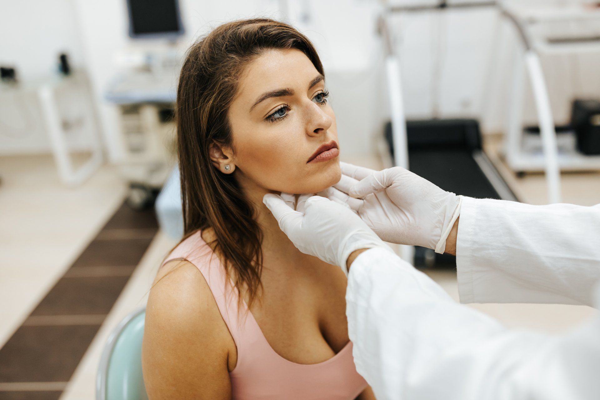 Woman having neck examined by a doctor in a clinic setting.