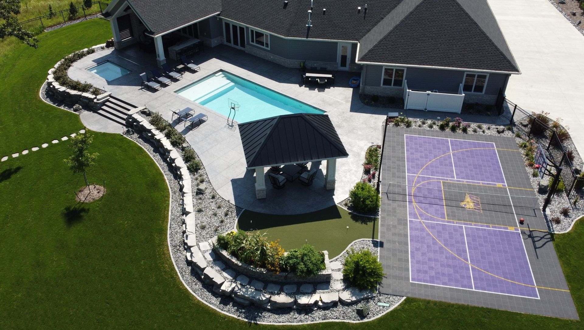 Aerial view of a home with a pool, gazebo, and sport court.