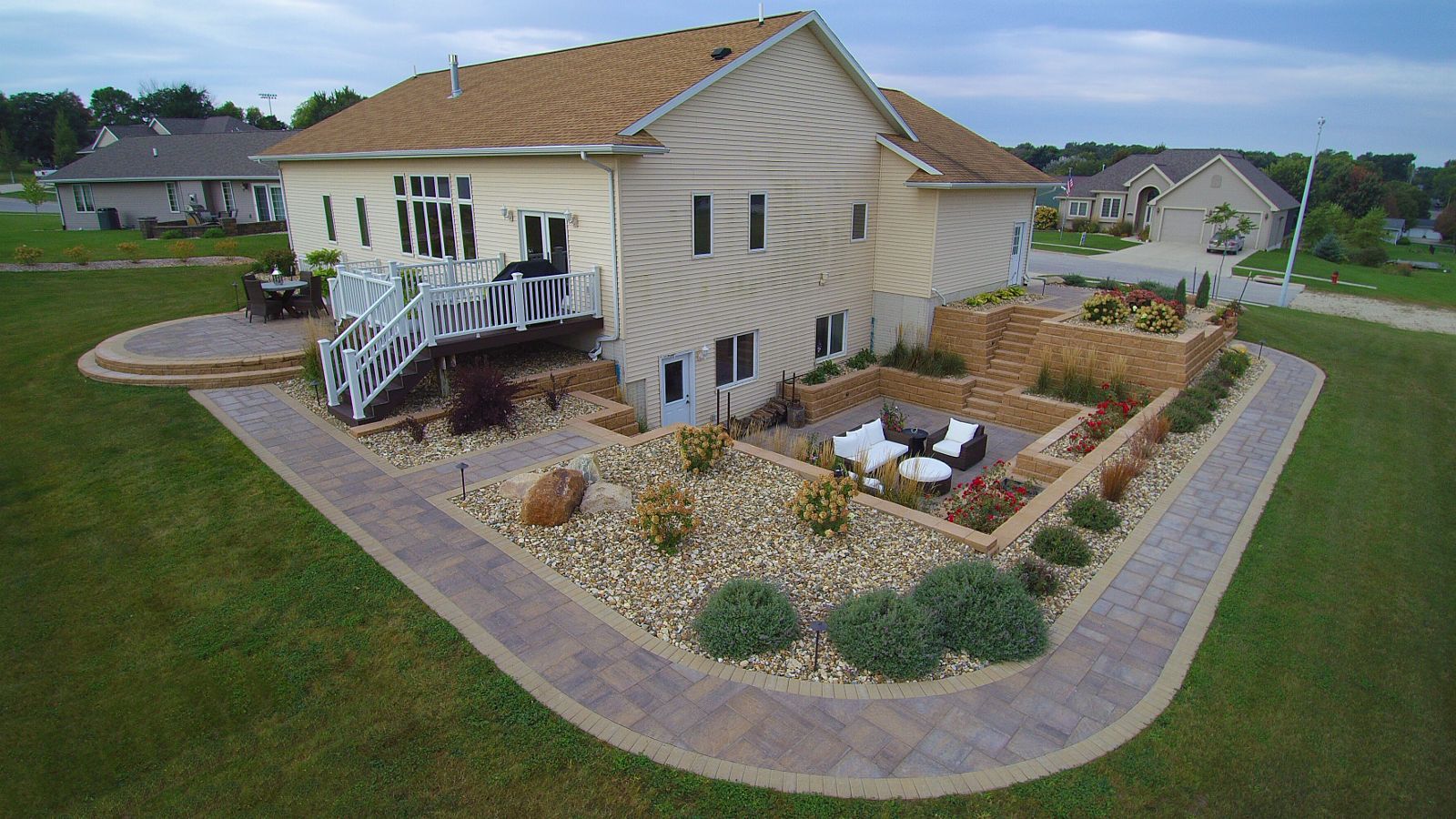 House exterior with landscaped patio, tan siding, and curved walkway.