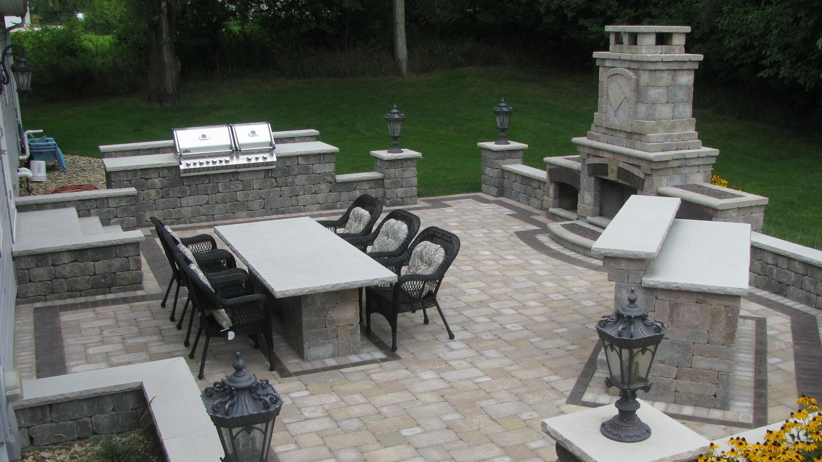 Outdoor patio with stone grill, fireplace, dining table, and lanterns.