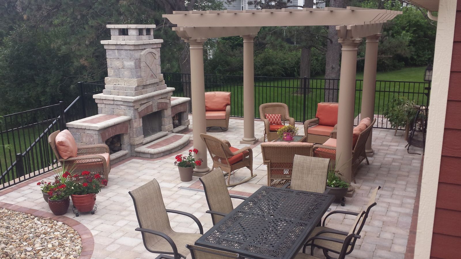 Patio with fireplace, seating area, pergola, and dining table, all on brick pavers.