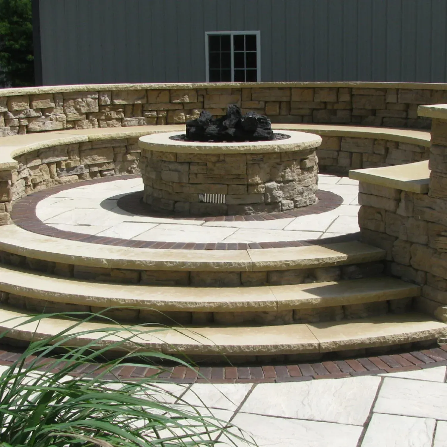 A fire pit is surrounded by a stone wall and steps — Waterloo, IA — Matthias Landscaping Co
