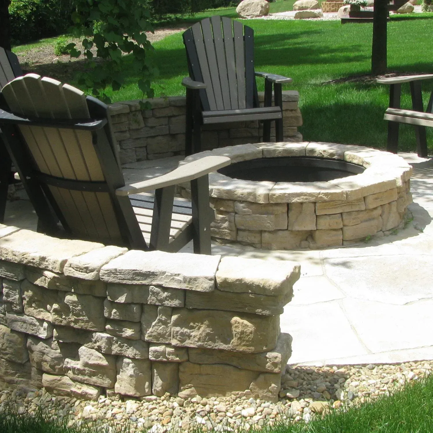 A fire pit surrounded by chairs and a stone wall — Waterloo, IA — Matthias Landscaping Co