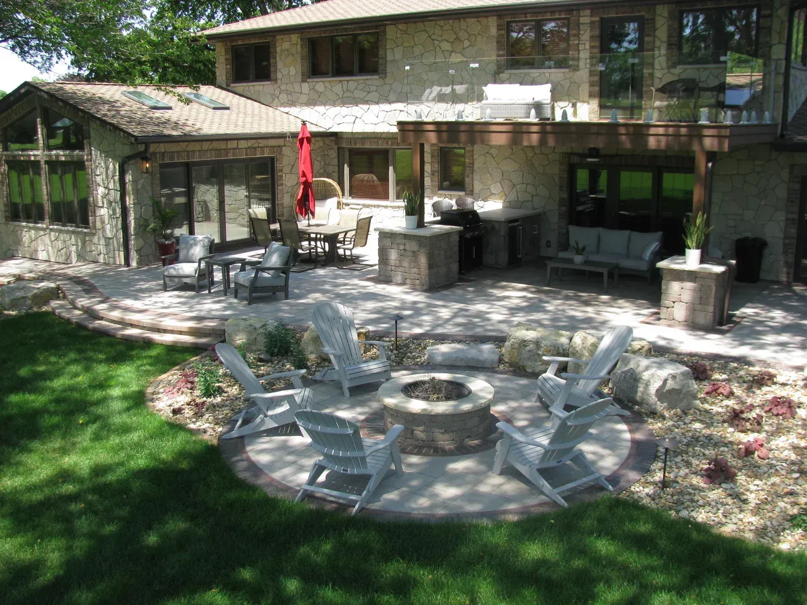 A patio with a fire pit and chairs in front of a house — Waterloo, IA — Matthias Landscaping Co