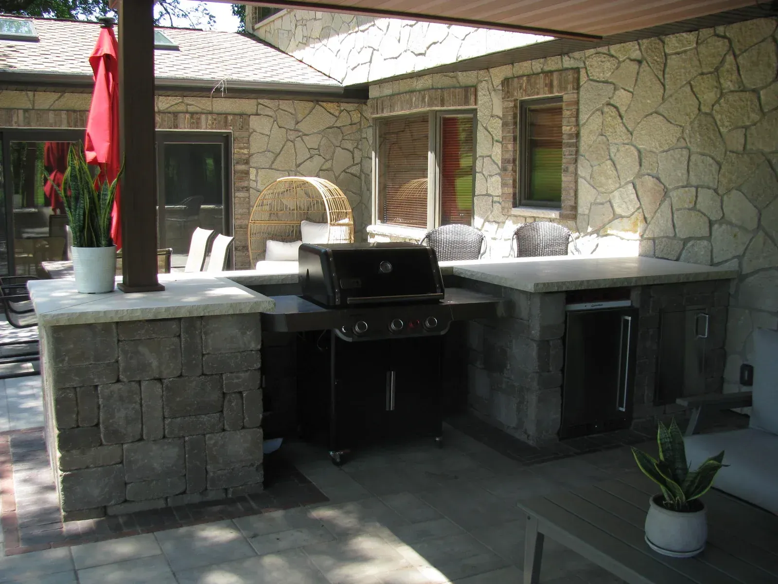A patio with a grill and a red umbrella — Waterloo, IA — Matthias Landscaping Co