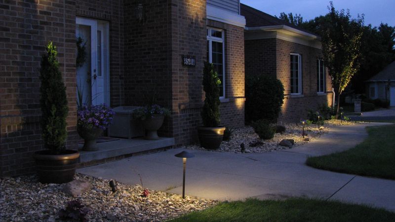 Brick house exterior with pathway lit by landscape lights at dusk.