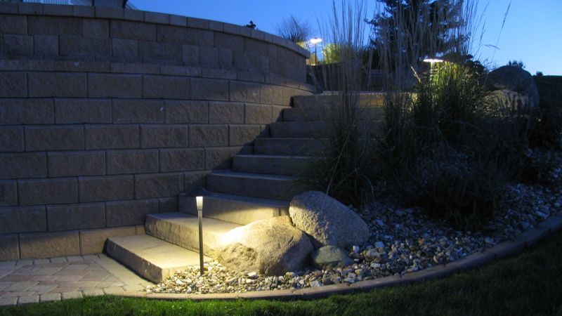 Stone steps illuminated by low lights, leading up a retaining wall at dusk.