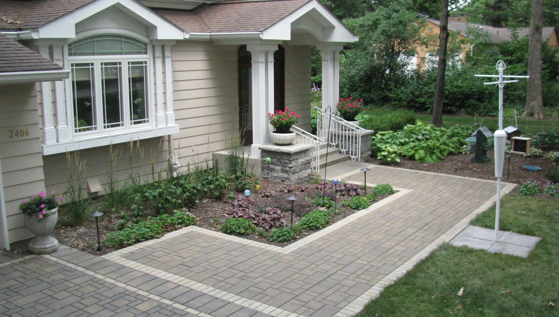 Brick walkway leading to a house with a small porch and landscaping.