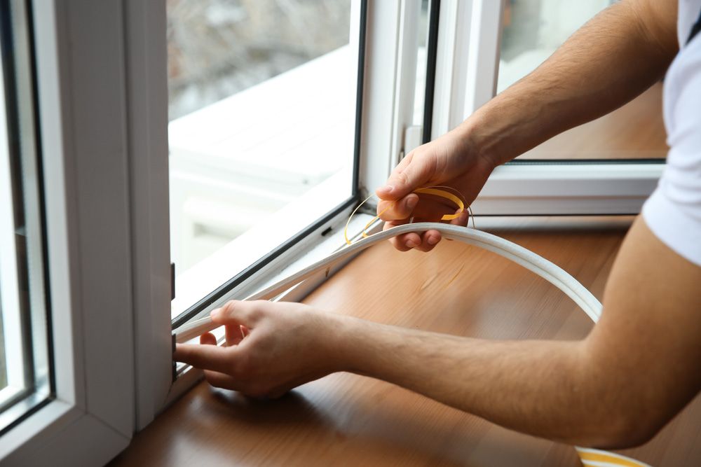 A Man is Installing a Window Seal on a Window Sill — Twin Cities Glass In Albury, NSW