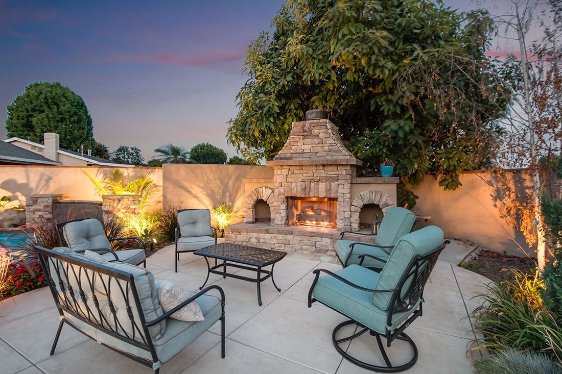 A patio with a fireplace , chairs , a couch and a table.