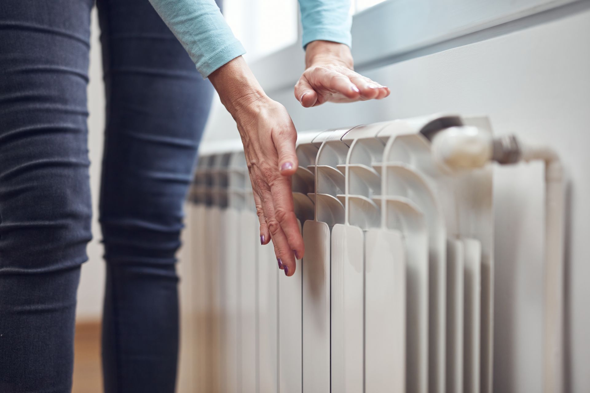 A woman is touching a radiator with her hand.