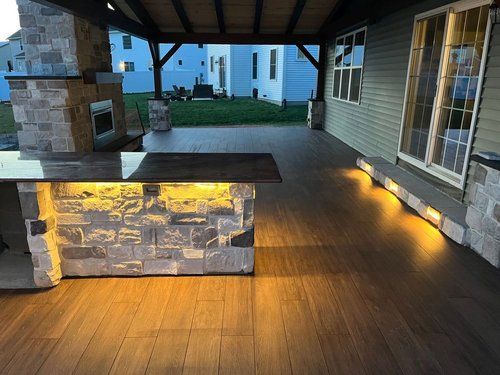 A patio with a stone fireplace and a wooden table with lights on it.