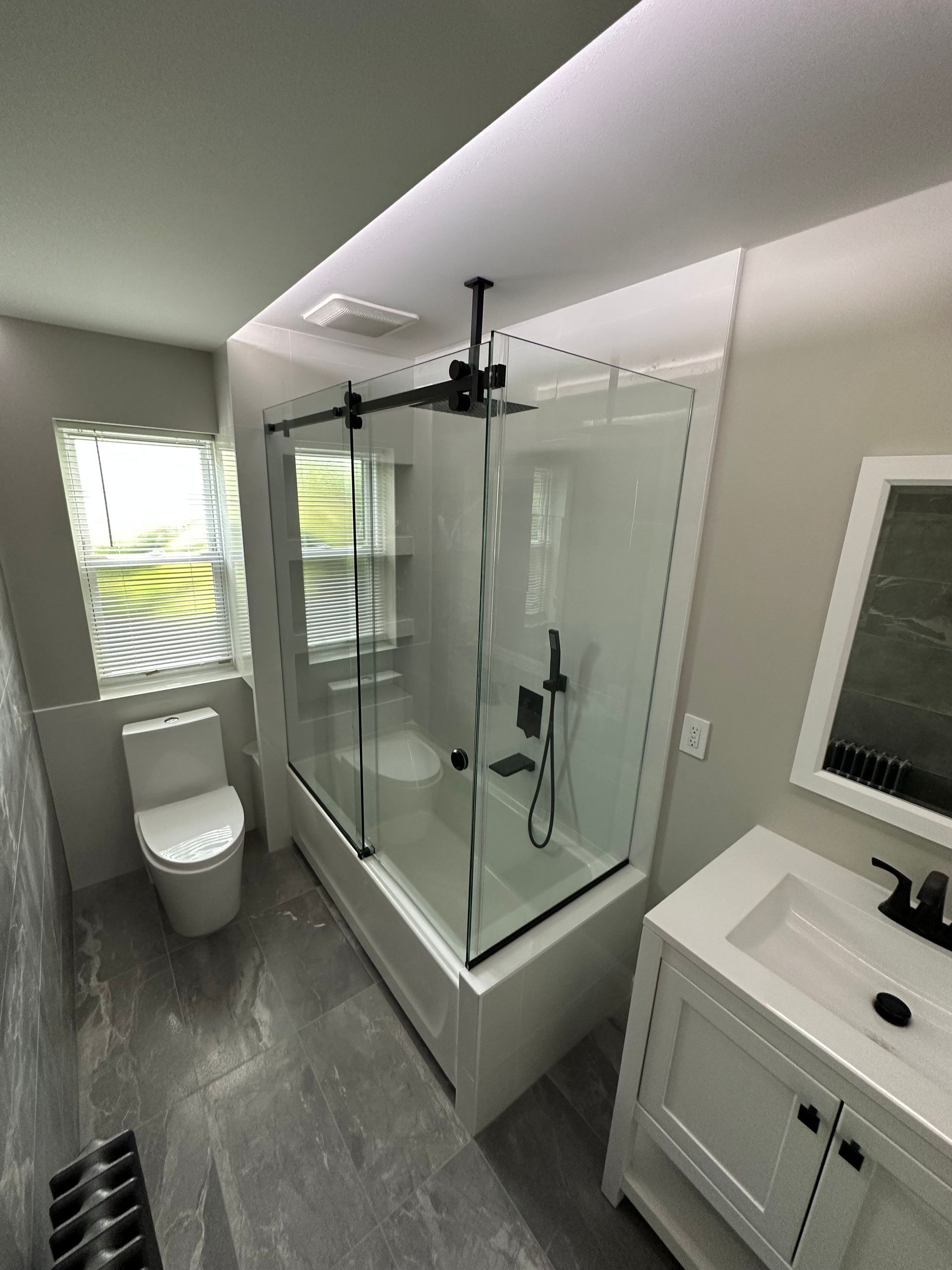 A bathroom with a tub , toilet , sink and mirror