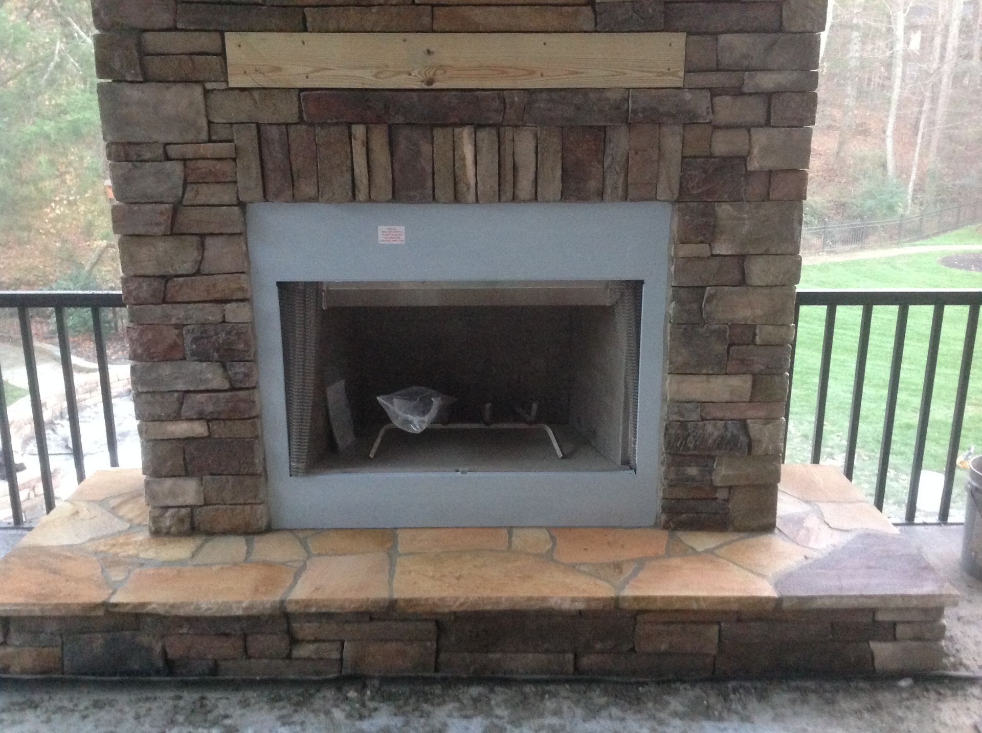 A brick fireplace is sitting on a patio next to a railing