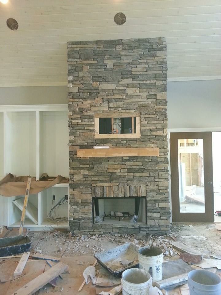 A stone fireplace is being built in a living room