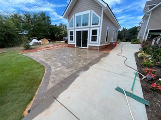 A house with a concrete driveway and a green broom in front of it.