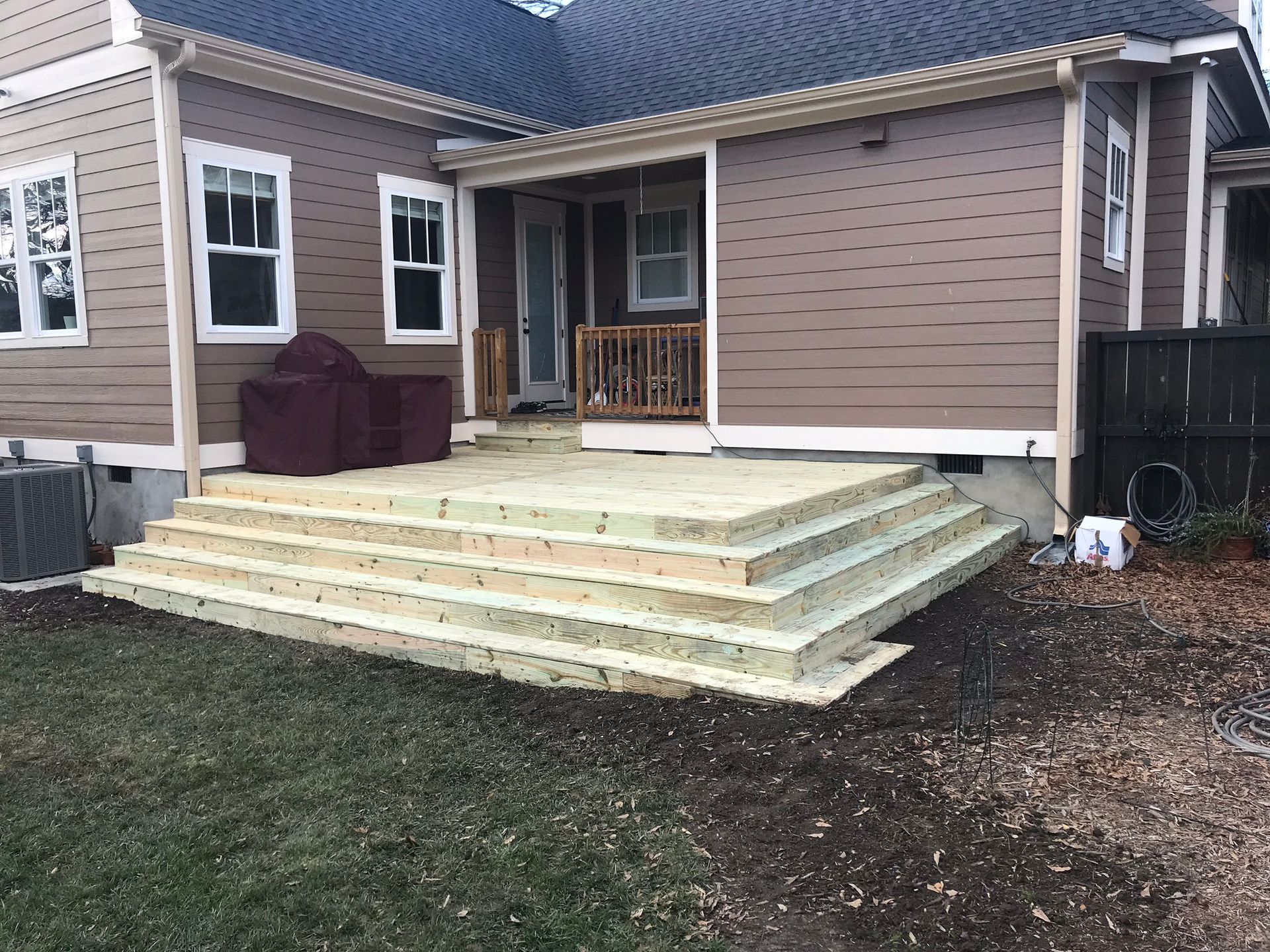 A house with a wooden deck and stairs in front of it.