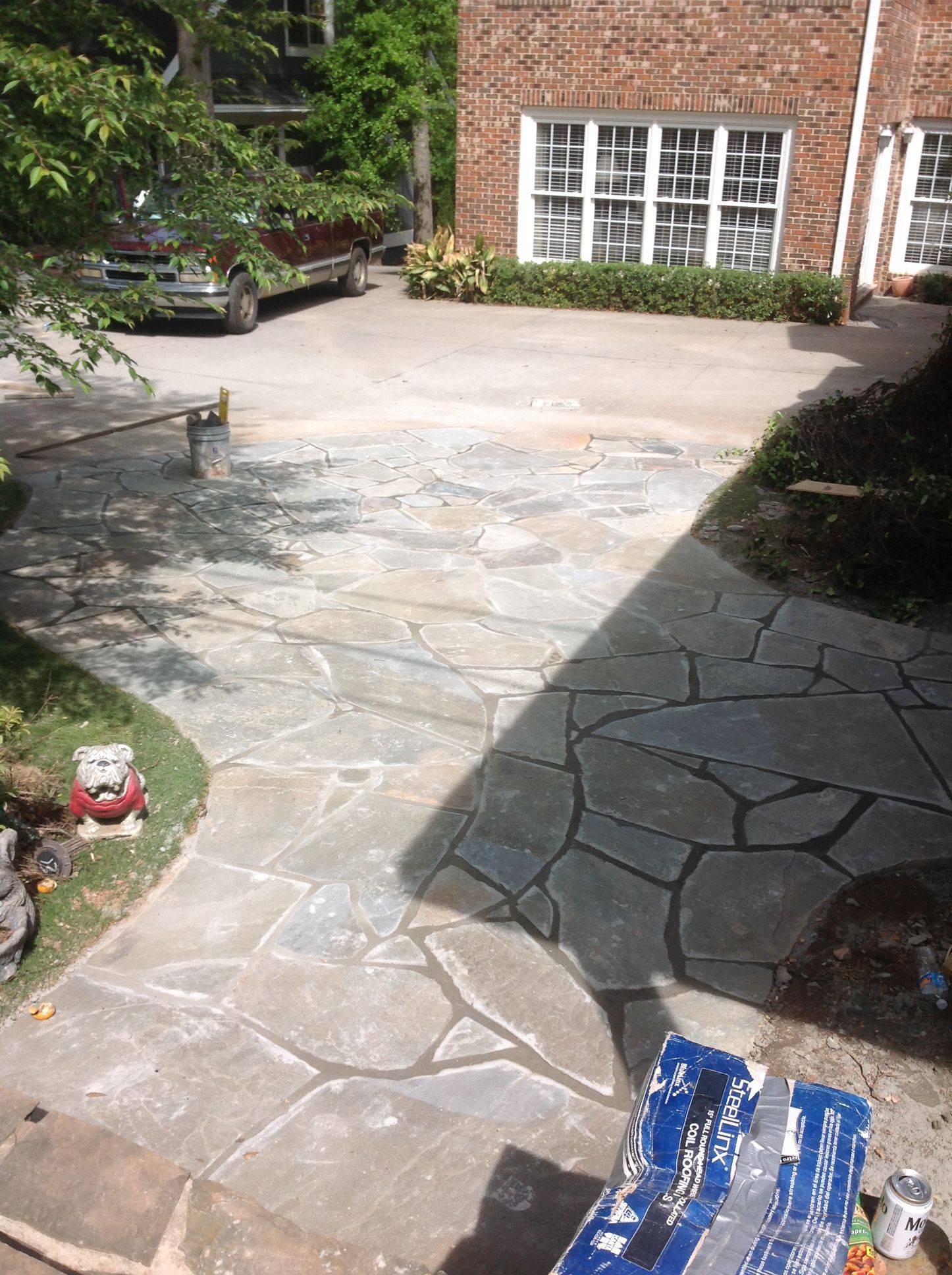 A stone patio is being built in front of a brick house.